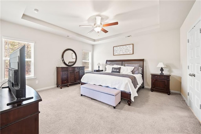 bedroom featuring a raised ceiling, ceiling fan, and light colored carpet