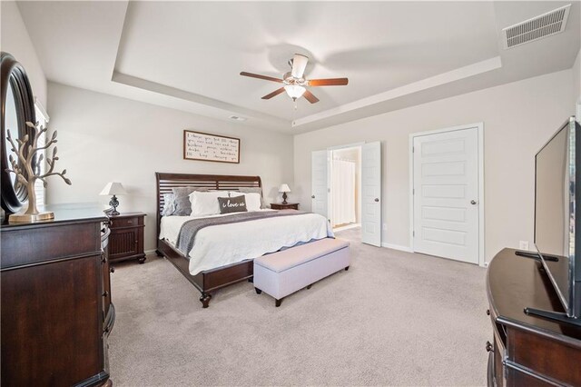 carpeted bedroom with a raised ceiling and ceiling fan