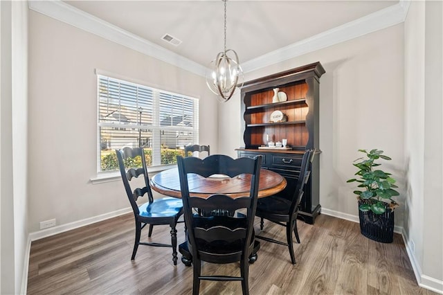 dining space featuring crown molding, hardwood / wood-style floors, and a chandelier