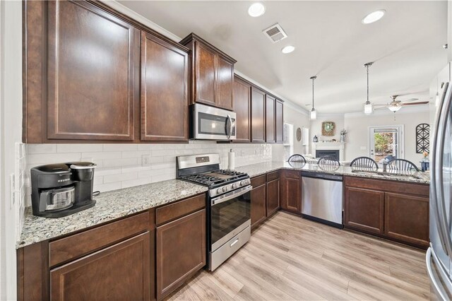 kitchen with kitchen peninsula, light wood-type flooring, backsplash, stainless steel appliances, and ceiling fan