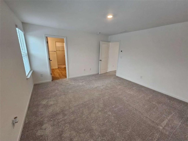 unfurnished bedroom featuring carpet flooring, a spacious closet, and a closet