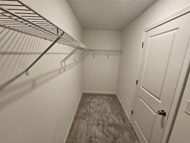 walk in closet with dark colored carpet