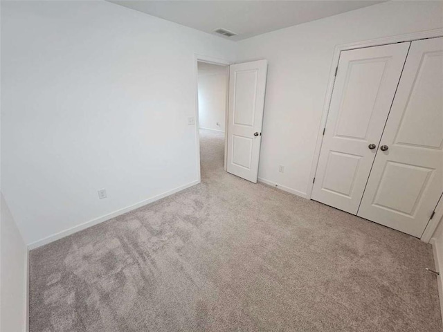 unfurnished bedroom featuring light carpet and a closet