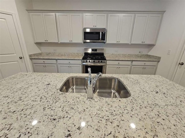 kitchen with light stone countertops, stainless steel appliances, and sink