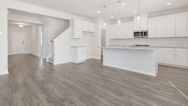 kitchen featuring white cabinetry, hanging light fixtures, and a kitchen island with sink