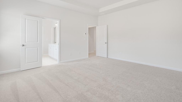 unfurnished bedroom featuring connected bathroom, light carpet, and a high ceiling