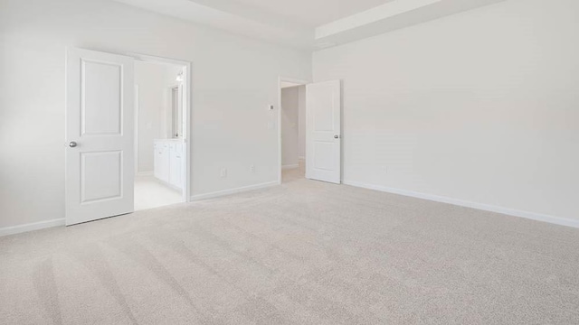 unfurnished bedroom featuring light carpet and ensuite bath