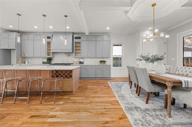 kitchen with hanging light fixtures, gray cabinets, sink, and a kitchen bar