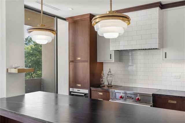 kitchen with tasteful backsplash, decorative light fixtures, oven, and range