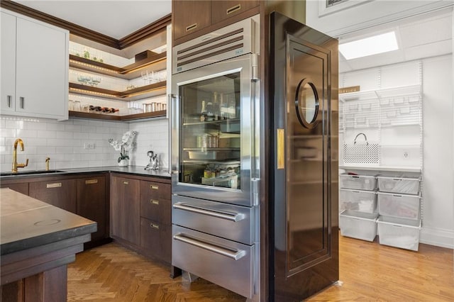 bar with sink, dark brown cabinetry, white cabinets, decorative backsplash, and light parquet flooring