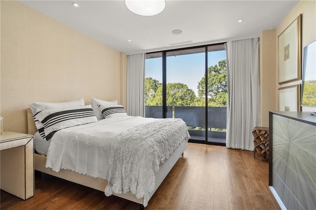 bedroom with floor to ceiling windows, access to outside, and dark hardwood / wood-style flooring