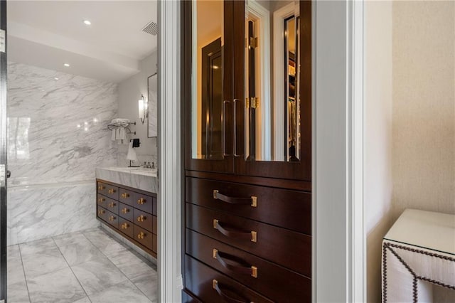 bathroom with vanity and tile walls