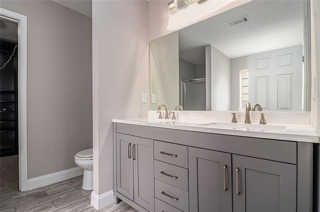 bathroom with double vanity, visible vents, a sink, a shower stall, and baseboards