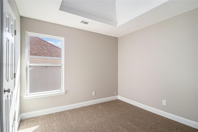 carpeted empty room with a raised ceiling, visible vents, and baseboards