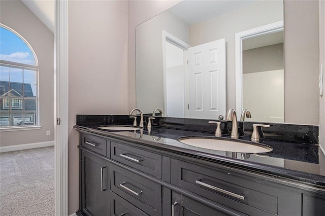 bathroom featuring double vanity, baseboards, and a sink