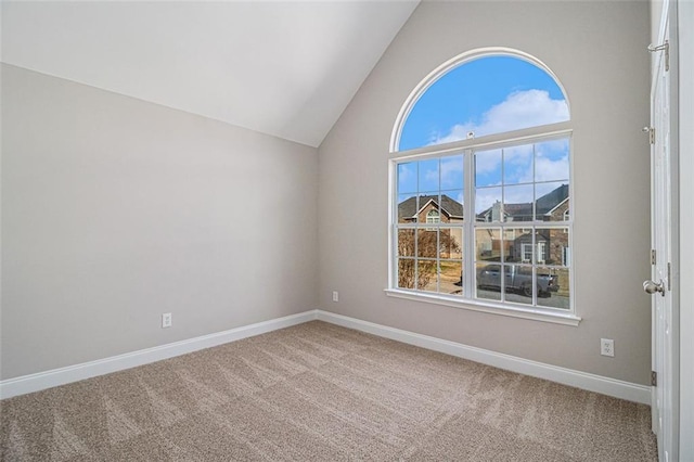 carpeted spare room featuring vaulted ceiling and baseboards