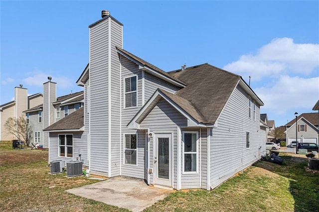 back of property featuring a yard, a chimney, a patio, a shingled roof, and central AC