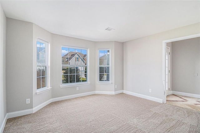 unfurnished room with baseboards, visible vents, and light colored carpet