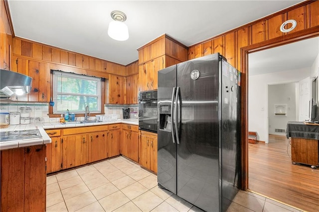 kitchen with black appliances, sink, light tile patterned floors, tasteful backsplash, and extractor fan