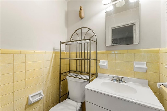 bathroom with vanity, toilet, and tile walls