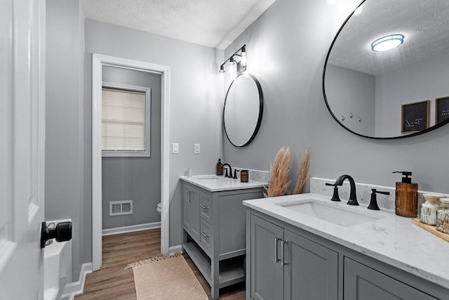 bathroom featuring hardwood / wood-style flooring, vanity, a textured ceiling, and toilet