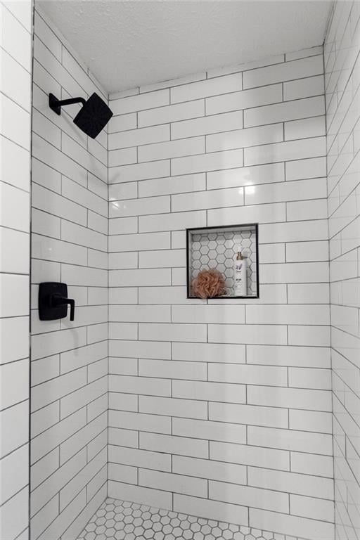 bathroom with a tile shower and a textured ceiling