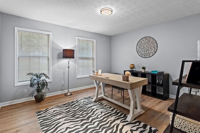 office area with light hardwood / wood-style floors and a textured ceiling