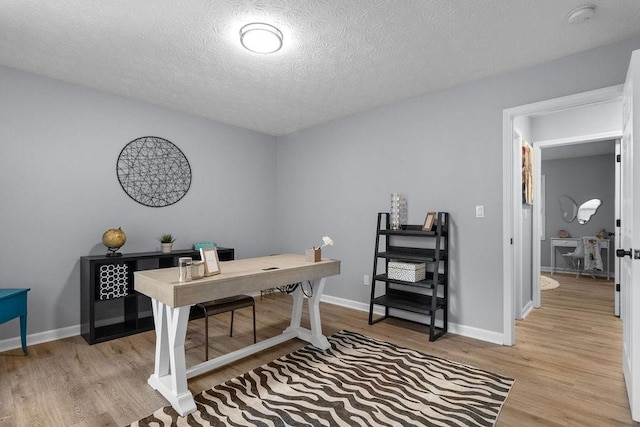 home office featuring light hardwood / wood-style floors and a textured ceiling