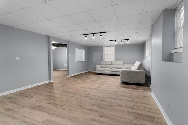 unfurnished living room with track lighting, a drop ceiling, and light hardwood / wood-style flooring