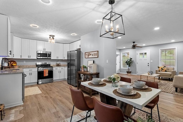 dining room with ceiling fan, sink, a textured ceiling, and light hardwood / wood-style flooring