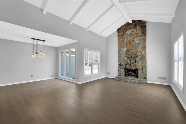 unfurnished living room with a notable chandelier, beamed ceiling, dark wood-type flooring, a stone fireplace, and high vaulted ceiling