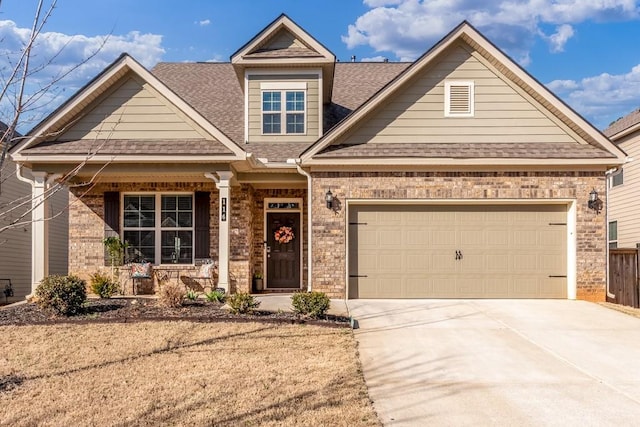 view of front facade with an attached garage, covered porch, brick siding, concrete driveway, and roof with shingles