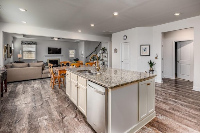 kitchen featuring recessed lighting, a fireplace, wood finished floors, a sink, and dishwasher