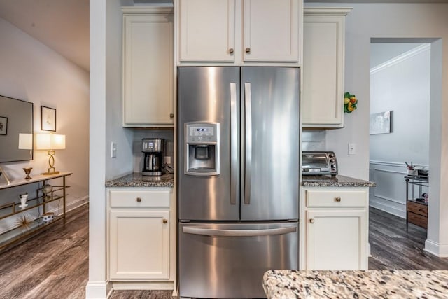 kitchen featuring crown molding, dark wood finished floors, stainless steel refrigerator with ice dispenser, and dark stone countertops