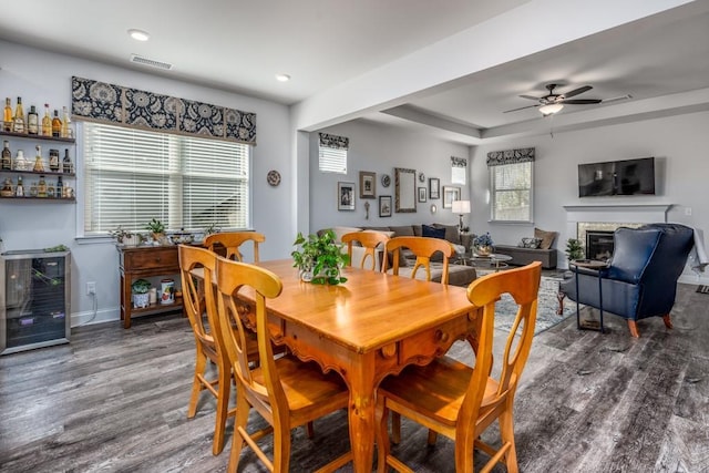 dining space with plenty of natural light, a raised ceiling, a glass covered fireplace, and dark wood finished floors