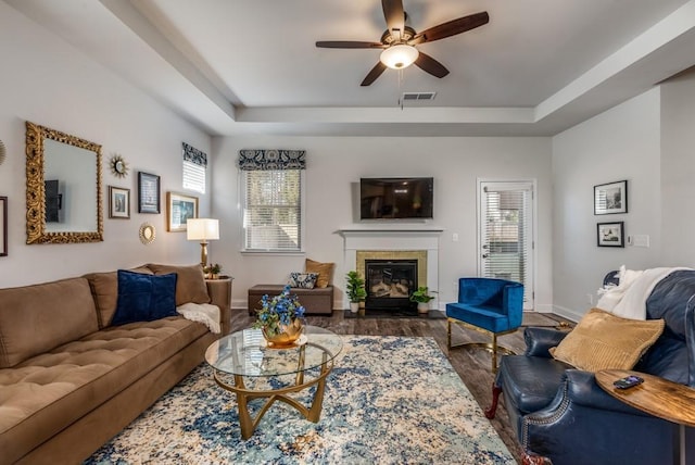 living area with a tray ceiling, visible vents, and plenty of natural light