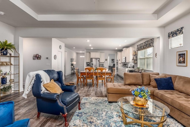 living area with a raised ceiling, dark wood finished floors, and recessed lighting