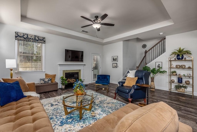 living area featuring a raised ceiling, baseboards, and wood finished floors