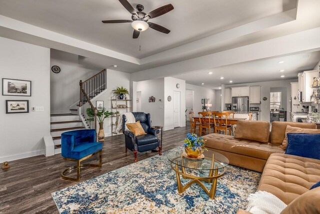 living area with baseboards, stairway, dark wood finished floors, and a raised ceiling