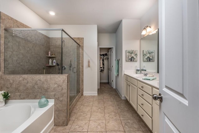 bathroom with tile patterned floors, a spacious closet, vanity, a shower stall, and a bath