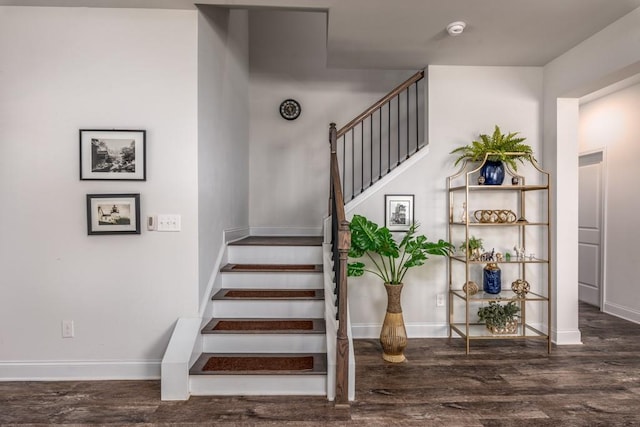 staircase featuring baseboards and wood finished floors