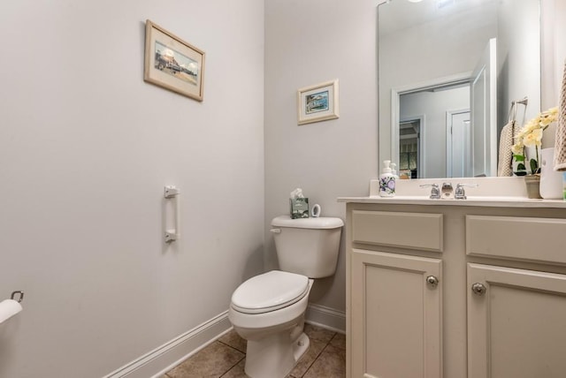 bathroom with toilet, vanity, baseboards, and tile patterned floors