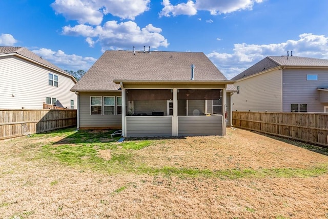 back of property with a sunroom, a fenced backyard, a shingled roof, and a yard