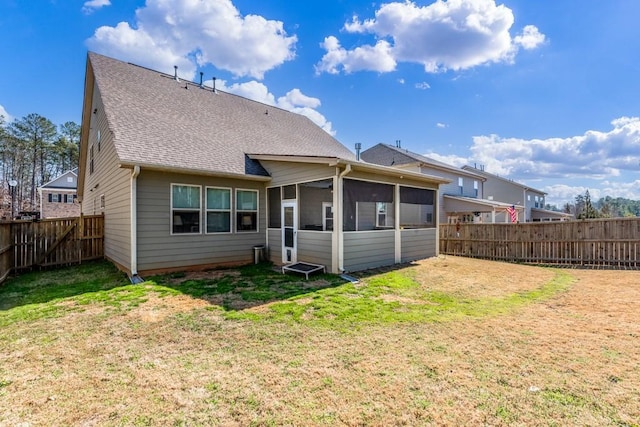 back of property with a sunroom, a fenced backyard, a yard, and roof with shingles