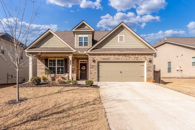 craftsman house featuring a garage, covered porch, brick siding, a shingled roof, and driveway