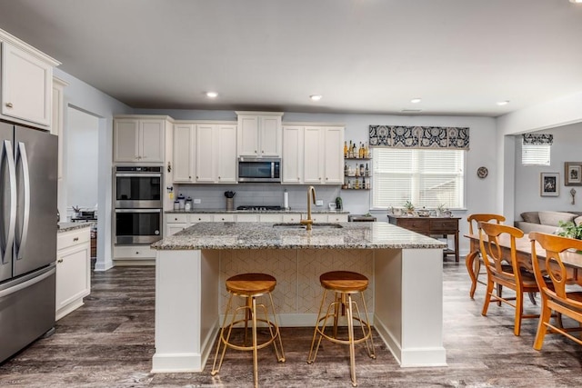 kitchen with stainless steel appliances, dark wood-style flooring, a sink, and a kitchen breakfast bar