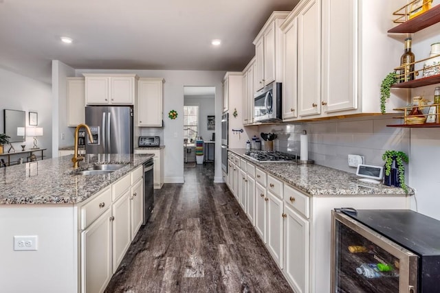 kitchen with open shelves, decorative backsplash, appliances with stainless steel finishes, a sink, and beverage cooler