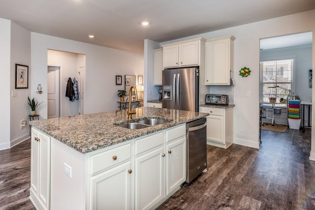 kitchen with dark wood-style floors, appliances with stainless steel finishes, a sink, light stone countertops, and baseboards