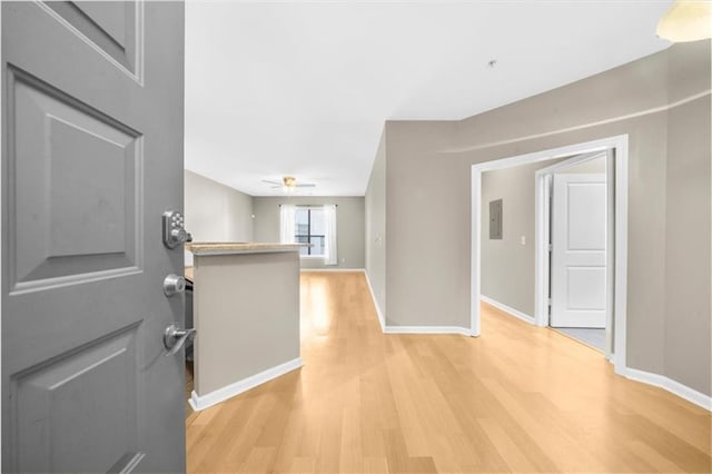 corridor with light hardwood / wood-style floors and electric panel