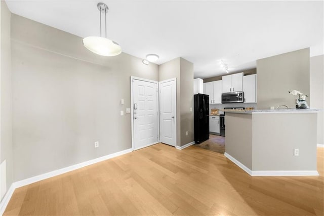 kitchen featuring appliances with stainless steel finishes, white cabinets, light hardwood / wood-style floors, and decorative light fixtures